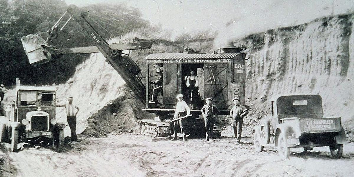 Early steam shovel with workers on a 1920s construction site